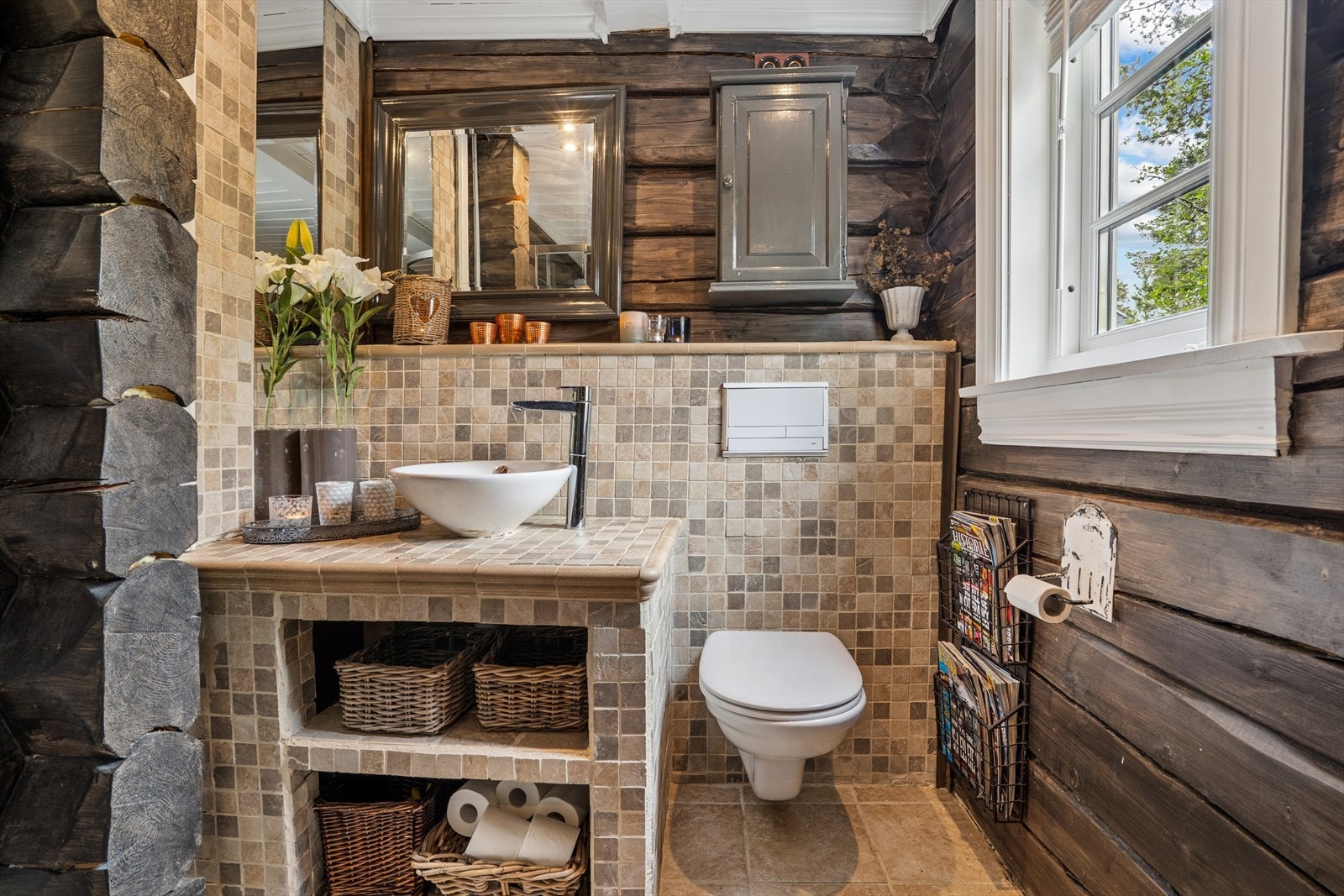 Badet er innredet med flislagt servant, veggmontert toalett og dusjkabinett. Galleribilde