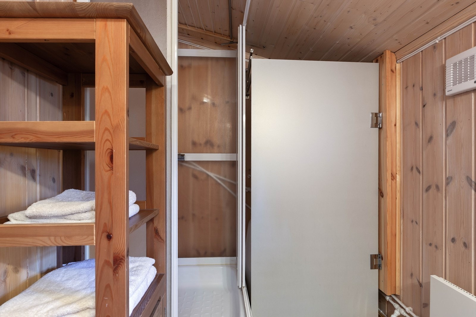 Rommet varmes opp med panelovn og det er montert ventilvifte i yttervegg. Vannbeholder/150 l tank, pumpe tilknyttet trykktank og liten varmtvannsbereder er skjult bak plexidør. Galleribilde