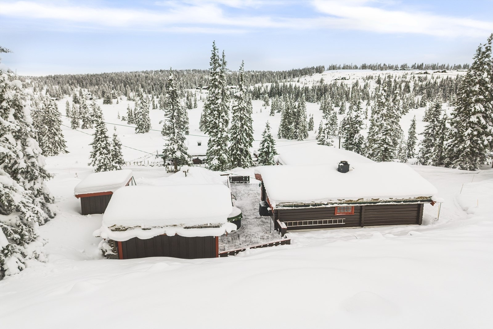 Eiendommen har en trivelig naturtomt med god plass til parkering, lek og moro. Bebyggelsen er pent tilpasset naturen, hvor hyttas opprinnelige del er oppført i laftet tømmer, og hvor både hytte og uthus har torv på taket. Galleribilde