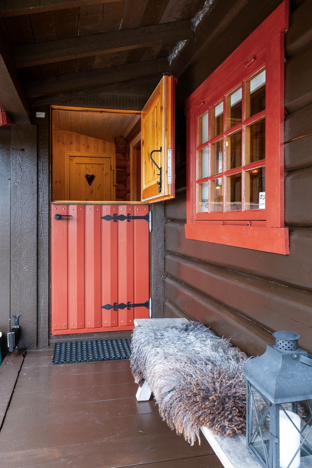 Hytta har et pent, overbygd inngangsparti med rødmalt stalldør som ønsker alle "Velkommen inn!" Galleribilde