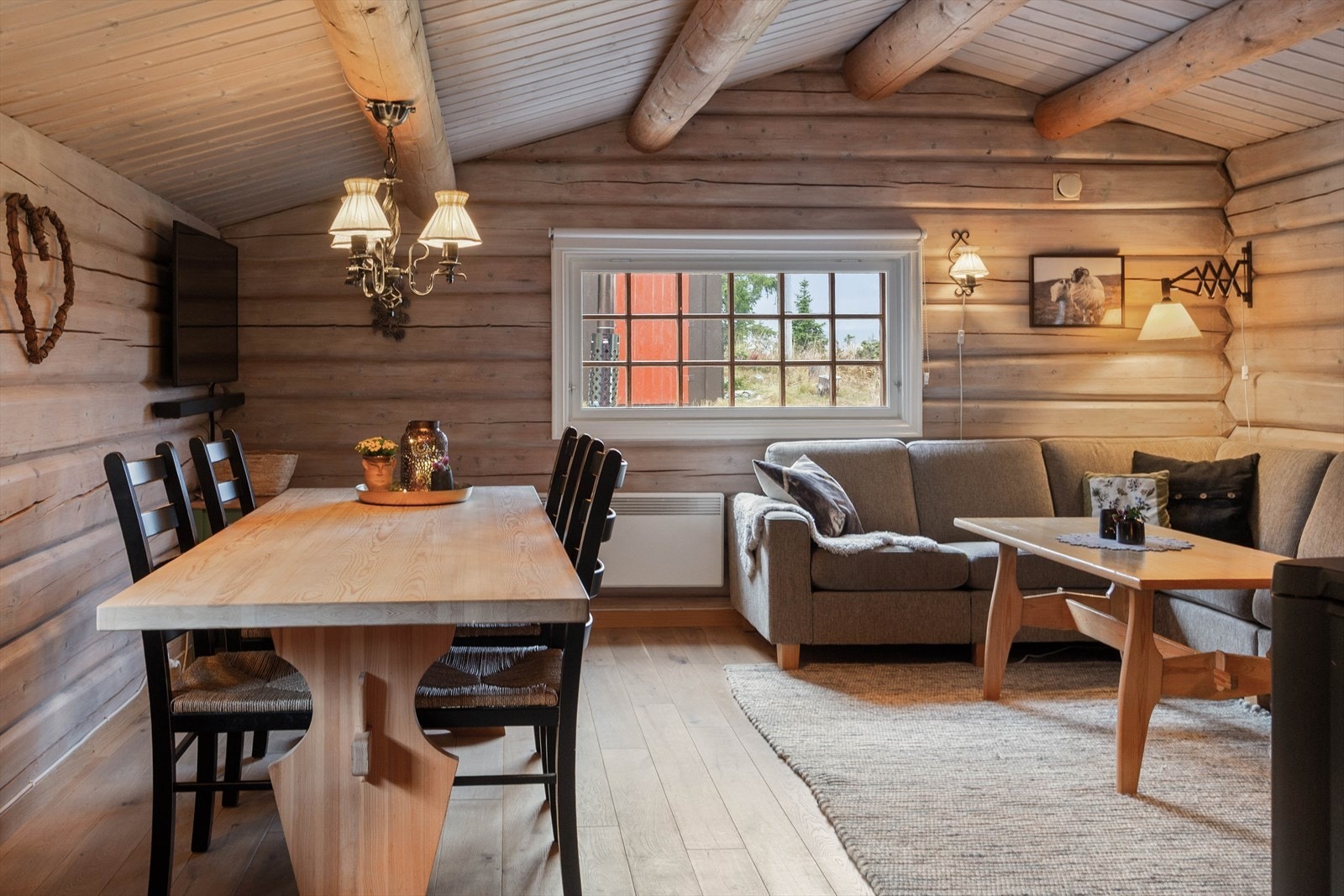 Inne i hytta er det en åpen og og luftig stue med flere vinduer og mønet himling med flotte tømmeråser. Galleribilde
