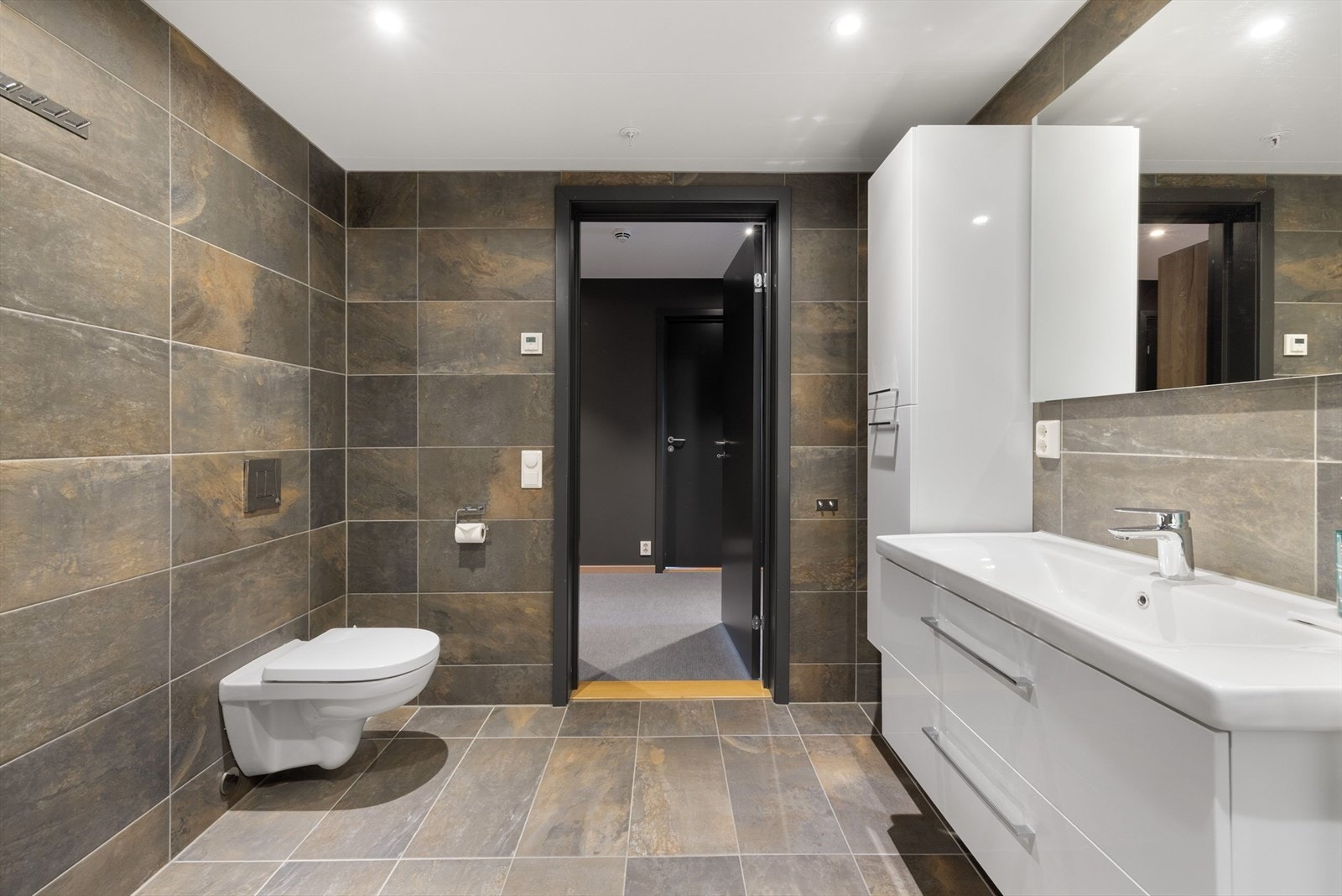 Baderom 1 er innredet med servant på innredning, dusjhjørne med glassvegger og vegghengt toalett. Galleribilde