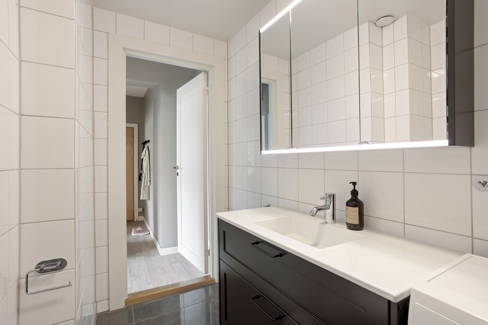 Videre har vi leilighetens bad. Her har du godt med oppbevaring i både speilskap og under servanten. Det er også opplegg for vaskemaskin. Vaskemaskinen medfølger. Galleribilde