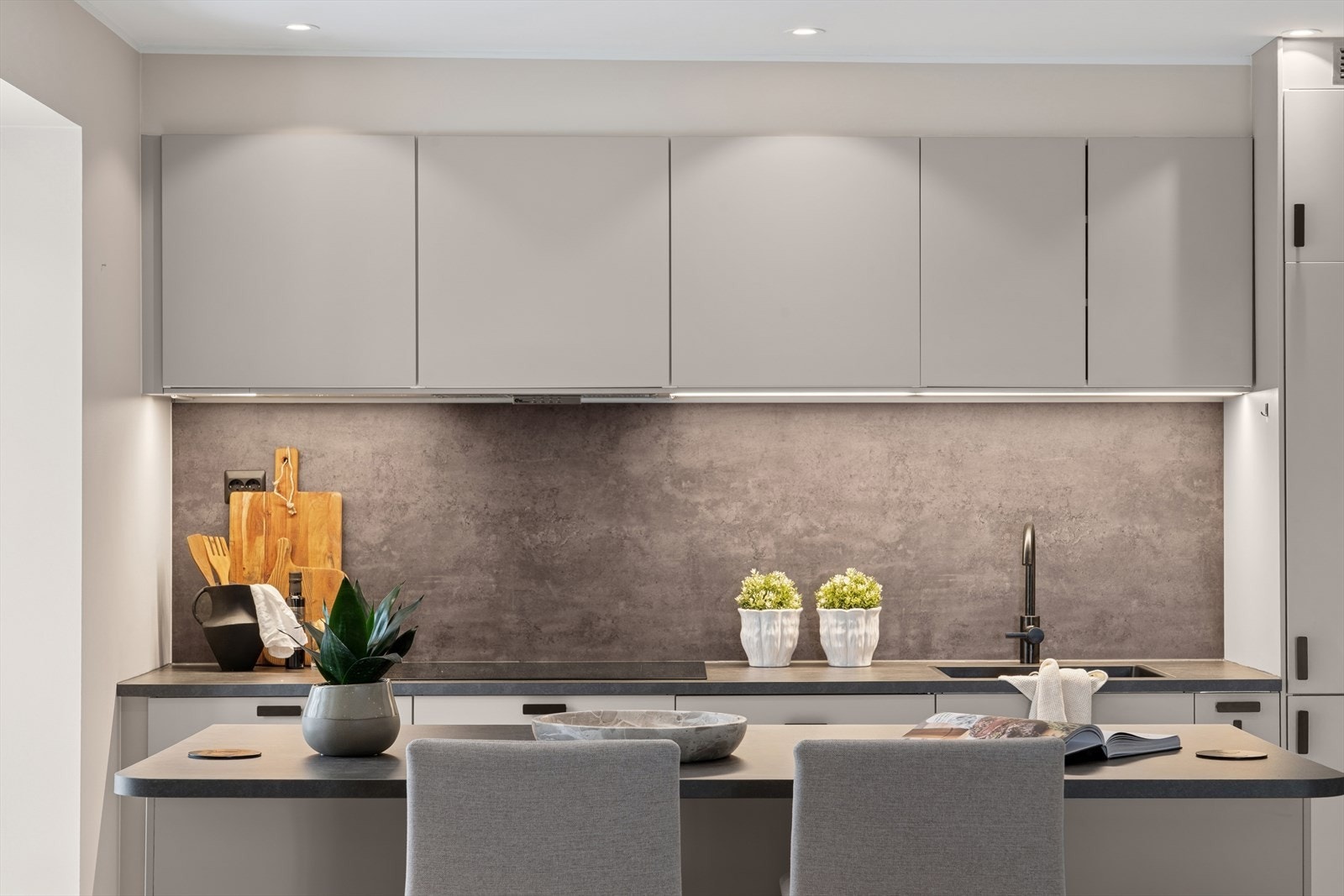 Mellom overskapene og benkeplaten er det montert en plate som fungerer som beskyttende og praktisk veggflate. Galleribilde