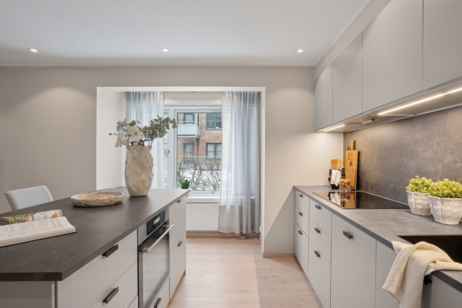 Et stort vindu ved kjøkkenet gir utsikt mot nærområdet og slipper inn rikelig med naturlig lys, noe som gjør arbeids- og spiseområdet lyst og trivelig. Galleribilde