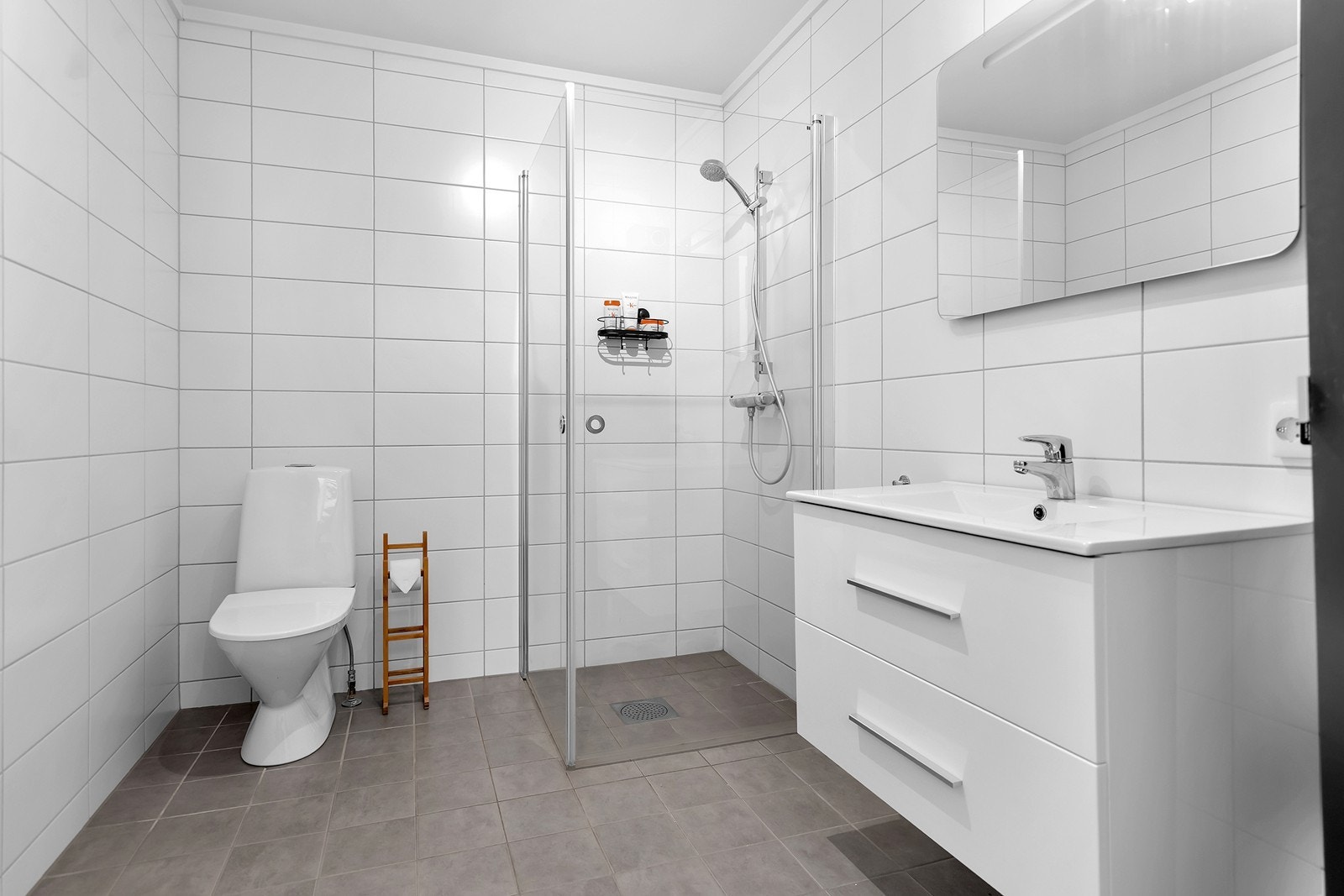 Romslig og flislagt bad i hovedetasjen (2. etasje) med dusjhjørne, moderne servantinnredning og god oppbevaringsplass. Galleribilde