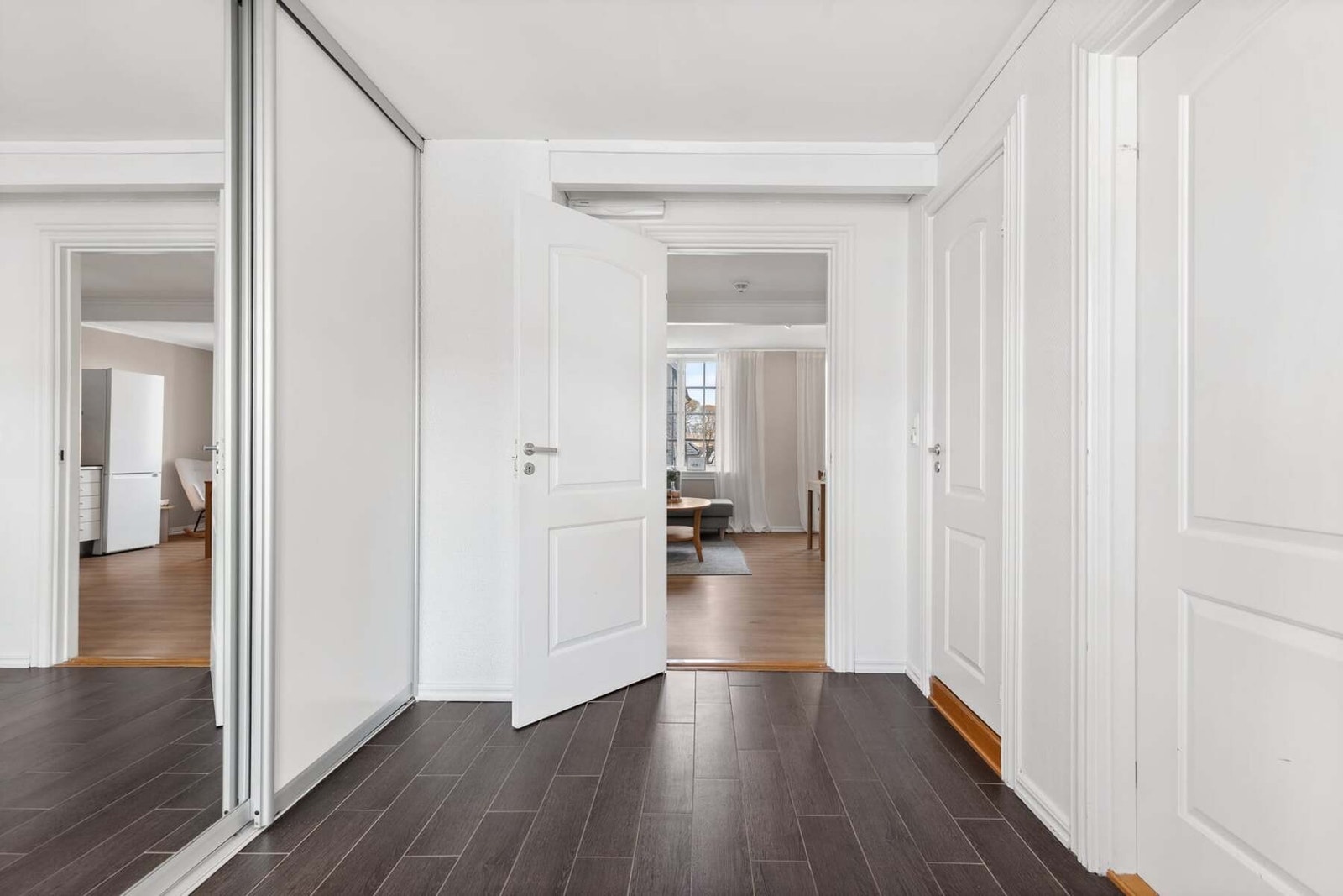 Det er montert en stor skyvedørsgarderobe med speilfront for oppbevaring av yttertøy og sko Galleribilde