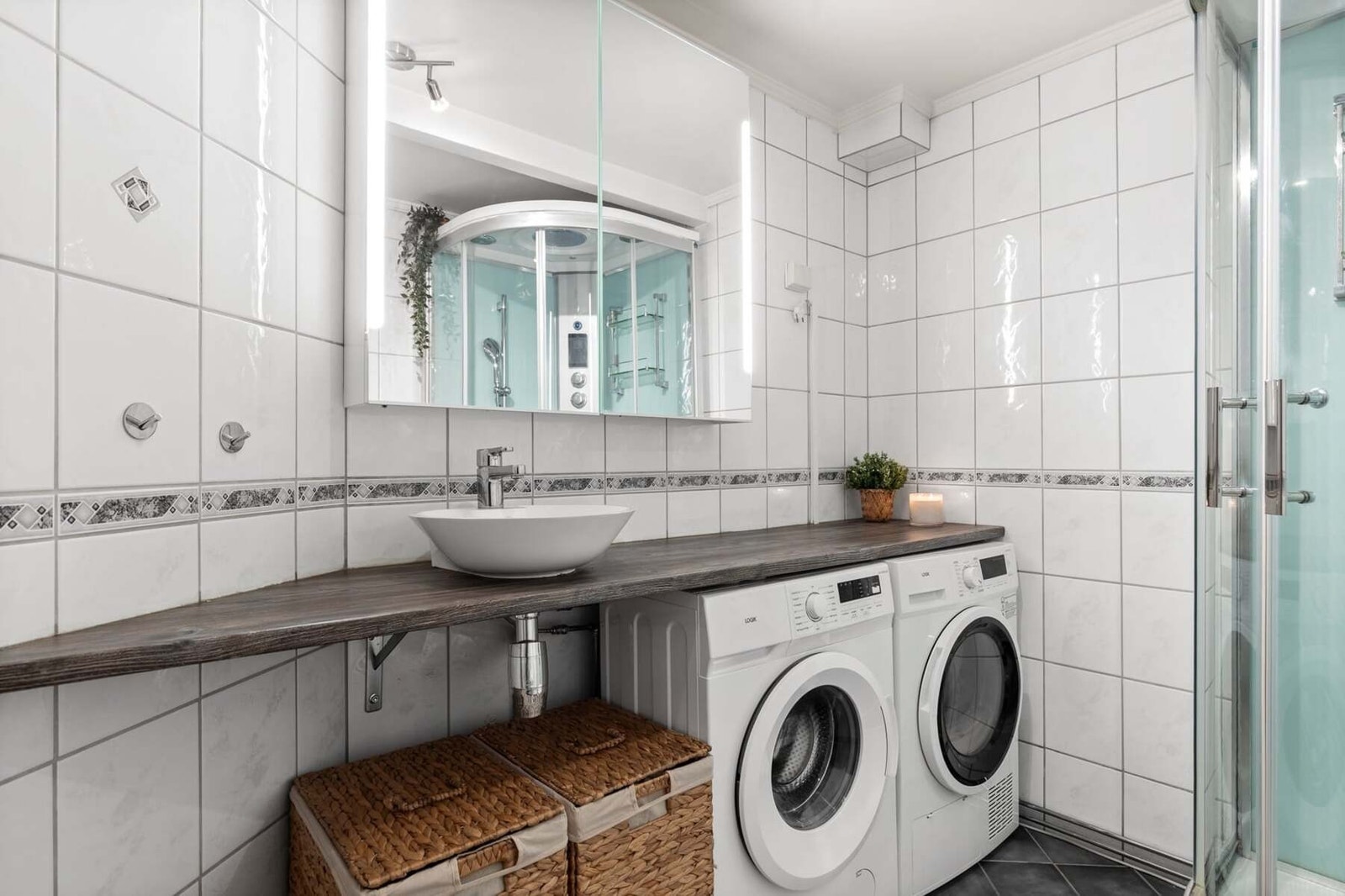 Badet er innredet med benkeplate med ovenpåliggende bolleservant og opplegg for vaskemaskin/tørketrommel Galleribilde