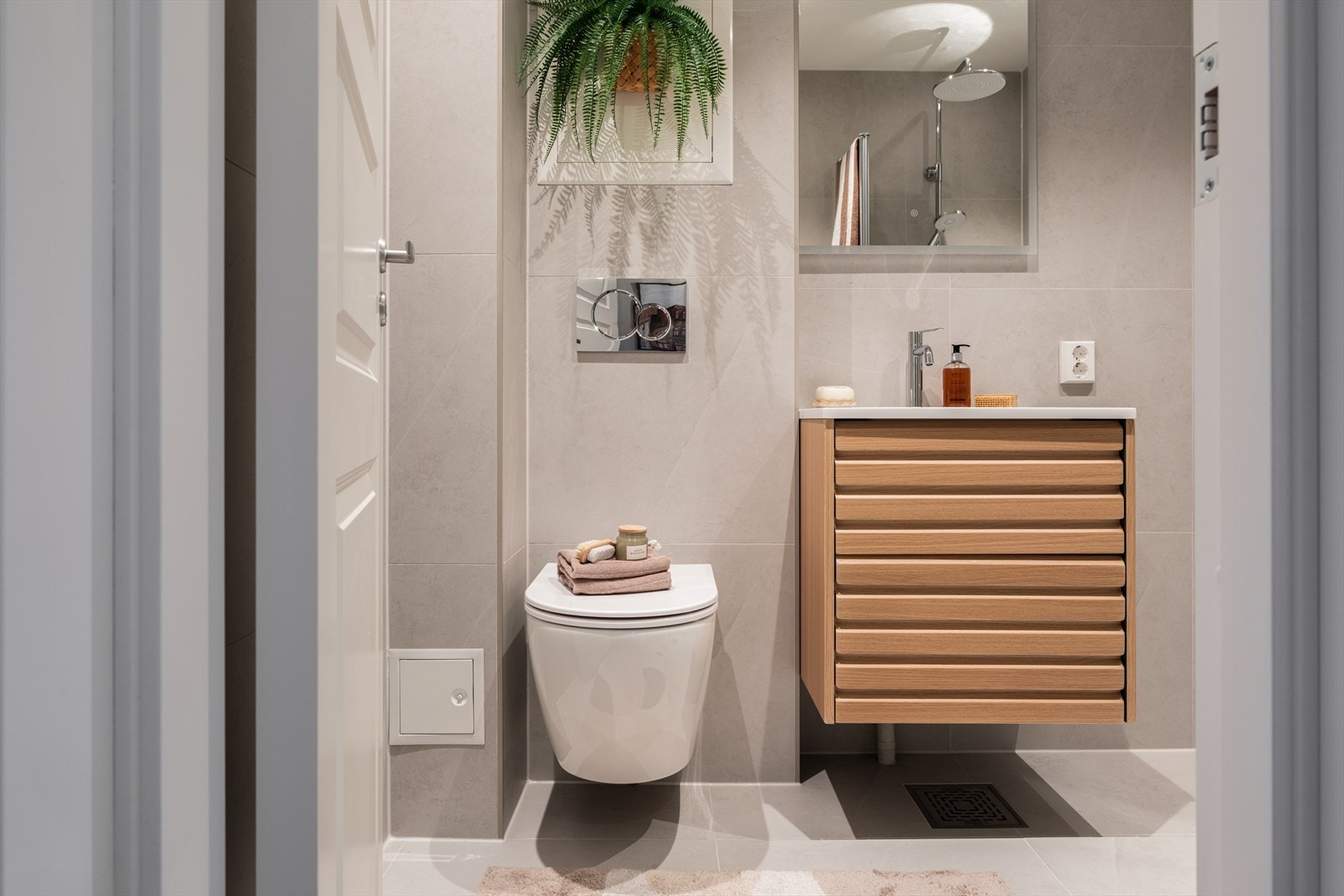 Delikat, flislagt bad med vegghengt toalett og en moderne baderomsinnredning. Galleribilde