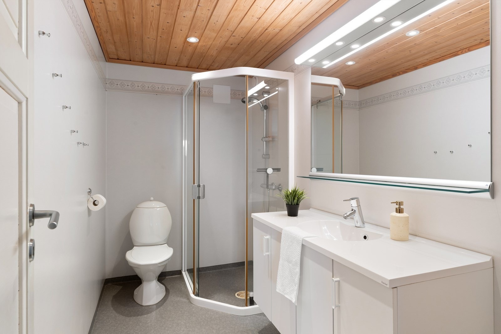 Badet i underetasjen er innredet med slitesterkt belegg på gulvet og våtromstapet på veggene. Her finnes dusjhjørne, vask i seksjon og toalett. Galleribilde