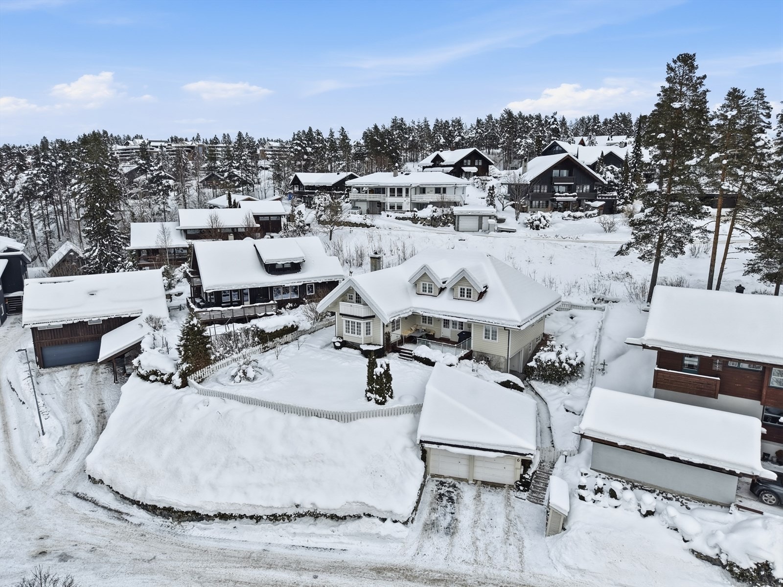 En attraktiv beliggenhet, umiddelbart nært til blant annet Madsebakken skole, som kan skimtes bak trærne til venstre til skrått opp til venstre for boligen. Galleribilde
