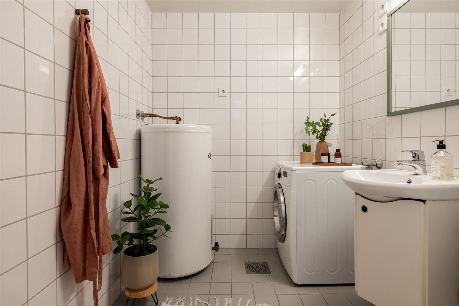 Rommet har flislagt gulv med varmekabler, opplegg for vaskemaskin og en 200L varmtvannsbereder. Galleribilde