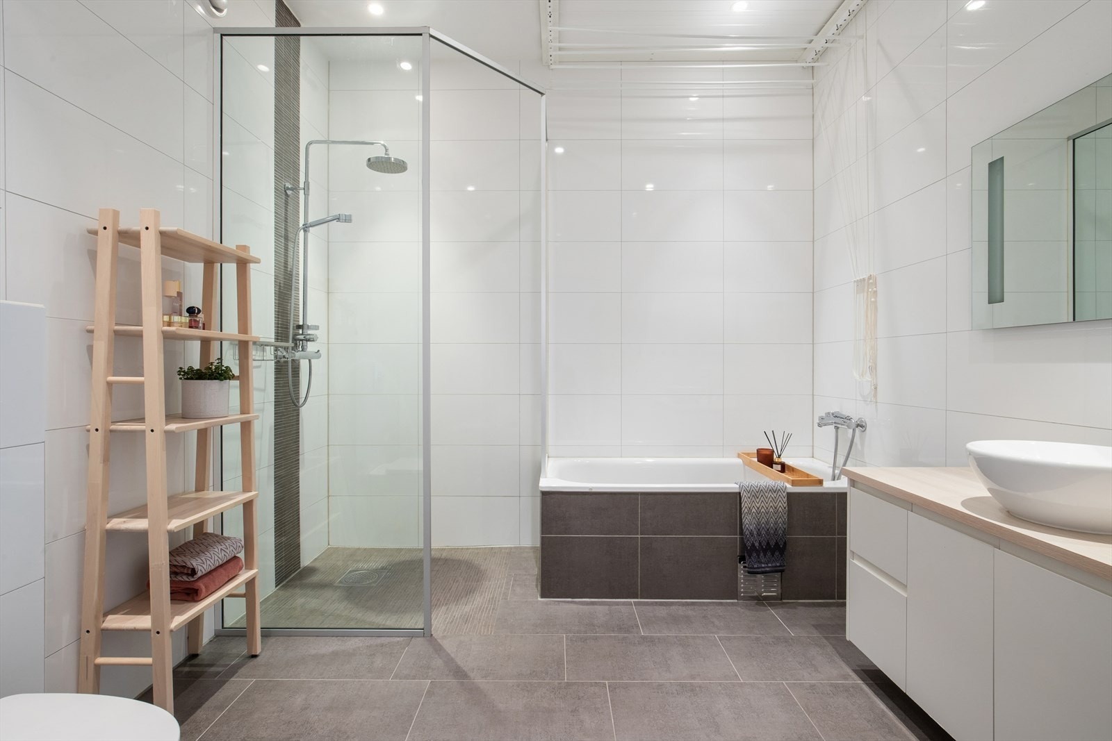 Badet er innredet med en servantinnredning, et dusjhjørne med glassvegger, et veggmontert toalett og et badekar. Galleribilde