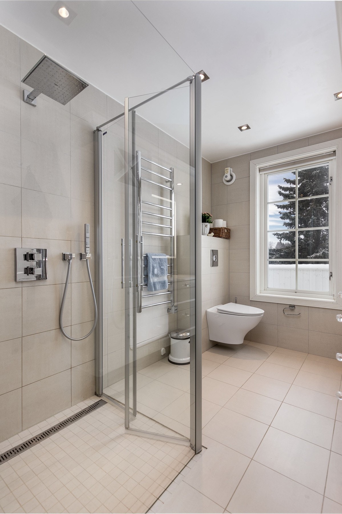 Badet inneholder profilert servantmøblement med over- og underskap, speil og toppmontert belysning, vegghengt toalett, samt separat dusjsone med glassvegger og regnfallsdusj. Galleribilde