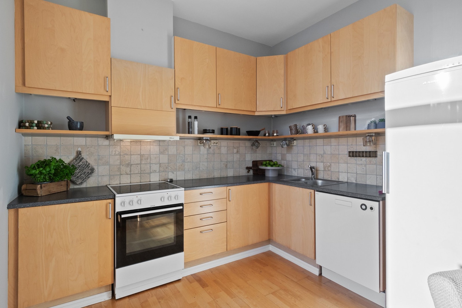 Kjøkkeninnredning med slette fronter. Laminat benkeplate med fliser over benk. Opplegg for oppvaskmaskin Galleribilde