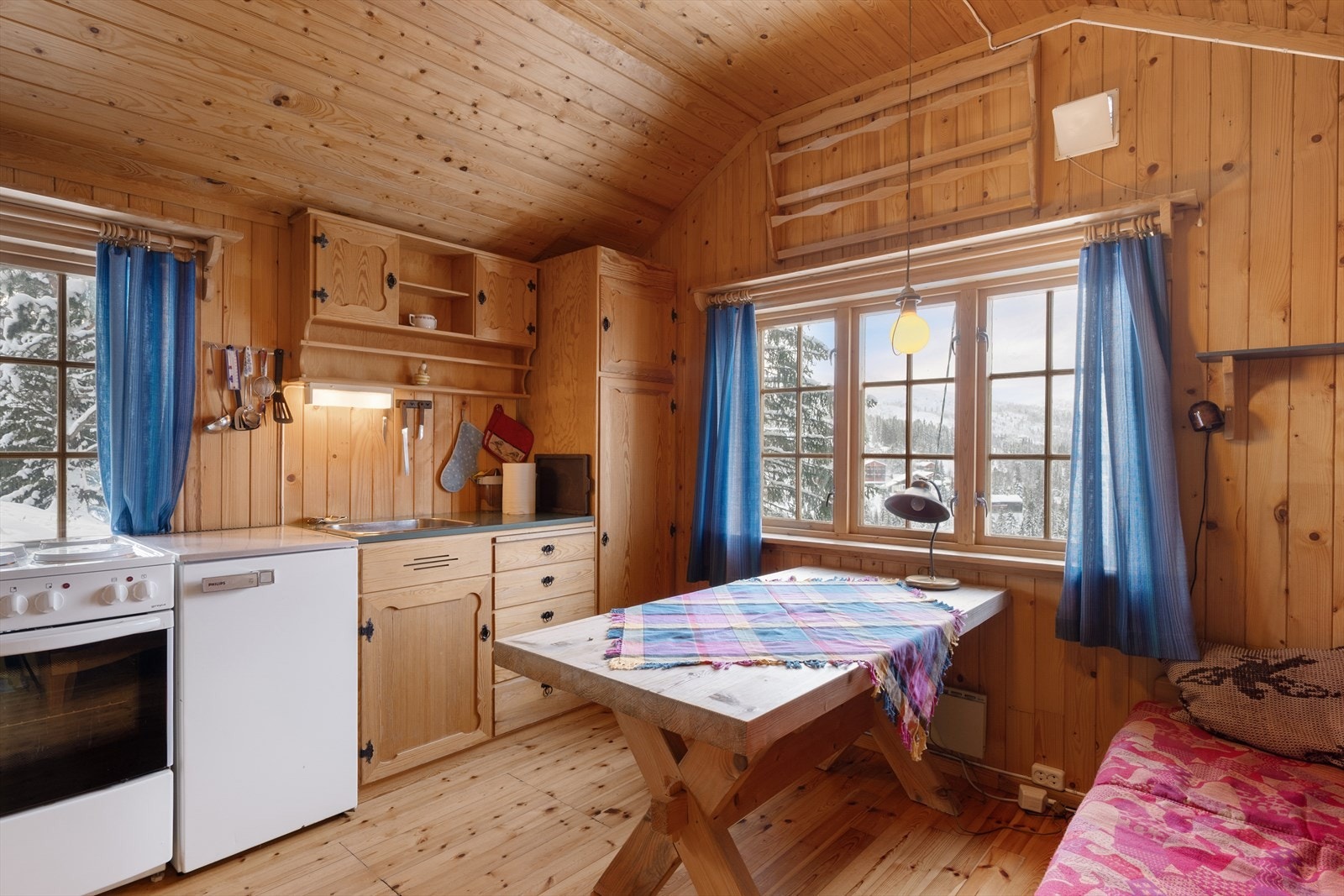 De koblede trevinduene med småruter gir godt med lys og rammer inn naturen utenfor. Galleribilde