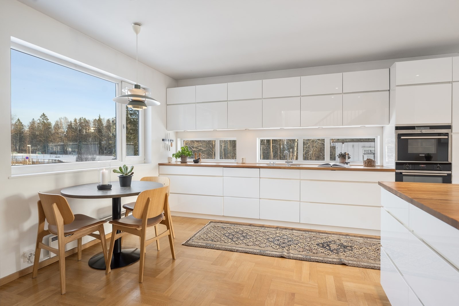 Kjøkkeninnredning med hvite grepsfrie fronter, heltre benkeplate med underlimt vask og blandebatteri Galleribilde