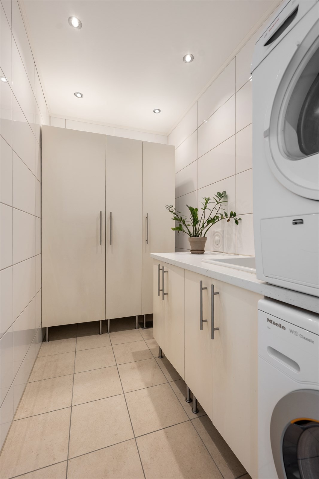 Lyst og praktisk vaskerom, innredet med utslagsvask og skapplass i underskap, samt flere høyskap. Opplegg for vaskesøyle. Det er klargjort med sisterne for veggmontert wc og røropplegg til dusj i rommet Galleribilde