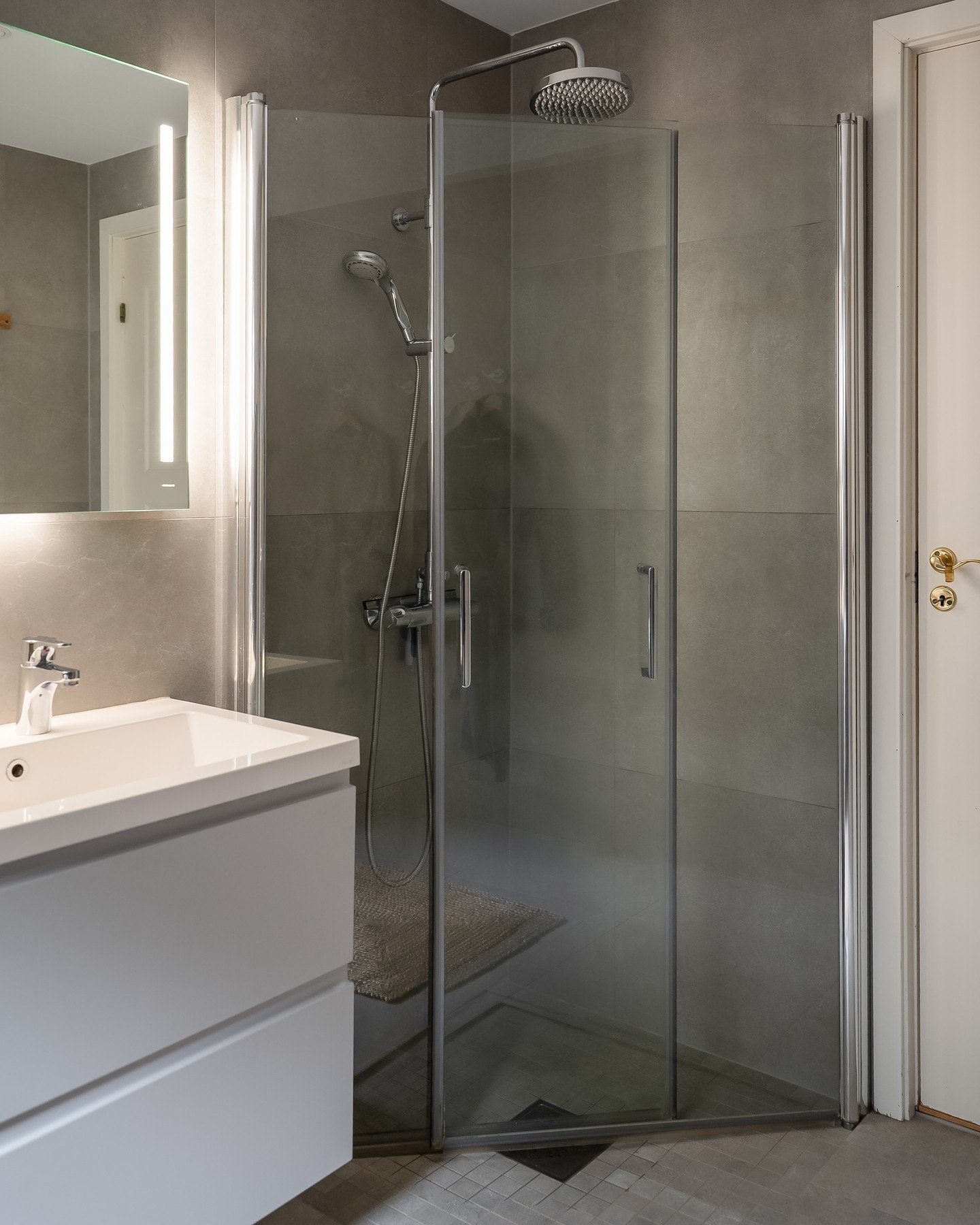 Dusjhjørne med glassvegger, regndusj og hånddusj. Vegger i grått. Galleribilde