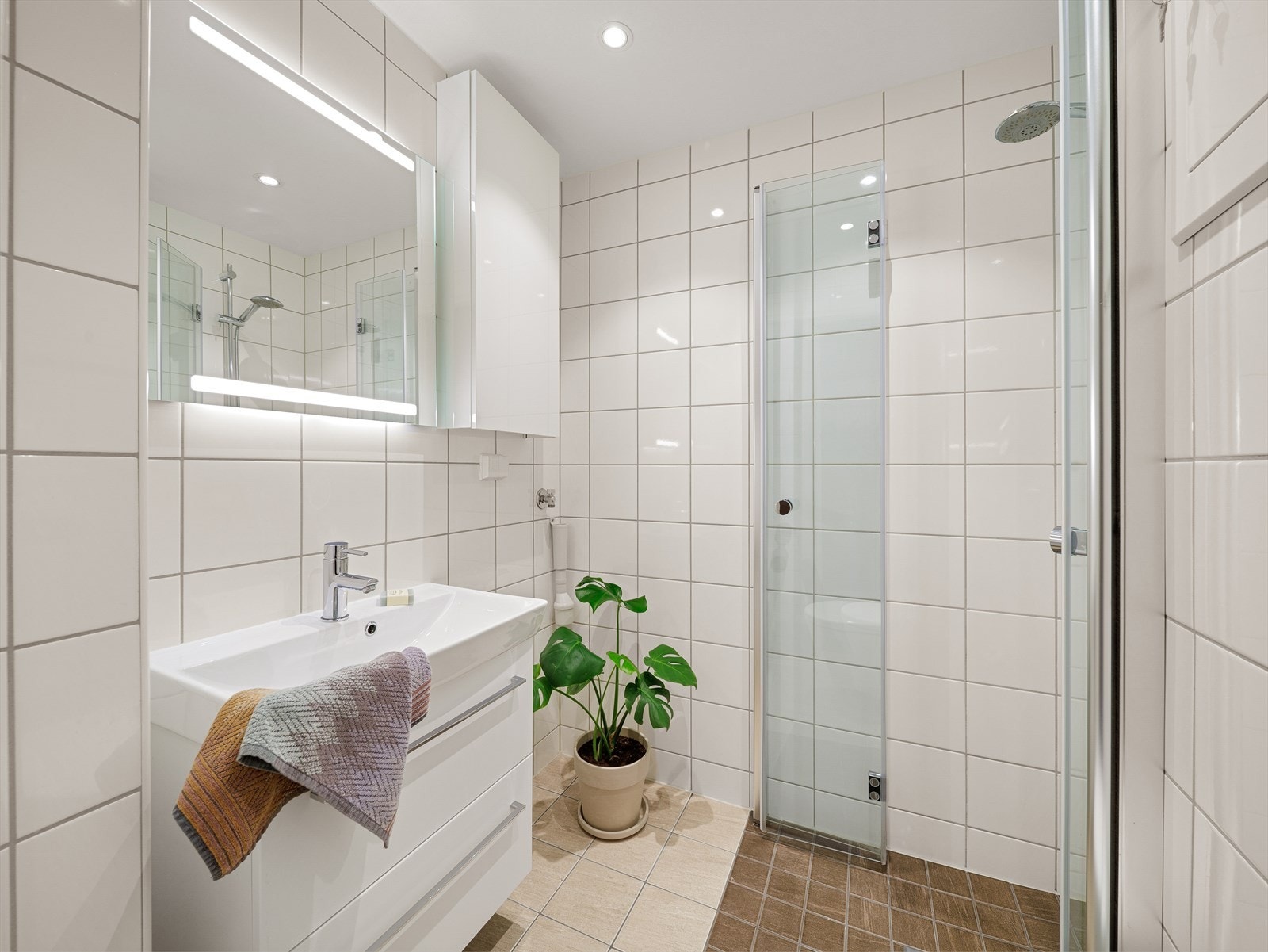 Leilighetens bad er helfliset og ble pusset opp i regi av borettslaget i 2018. Galleribilde