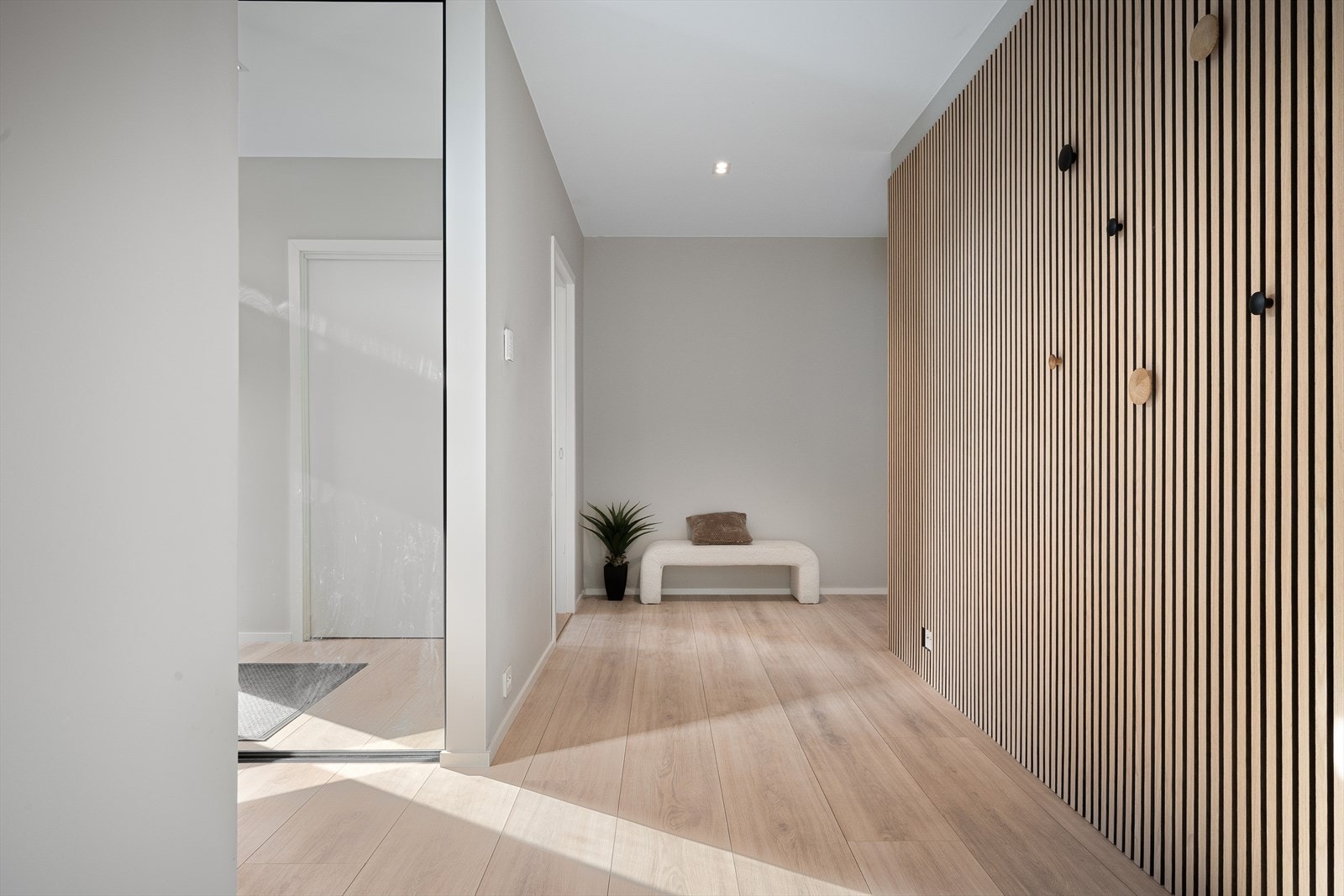 Romslig gang med skyvedørsgarderobe, spilevegg for kontrast. Oppheng og liten bod under trapp. Høytrykkslaminat fra Berry Alloc. Plass til flere kommoder og reoler. Galleribilde