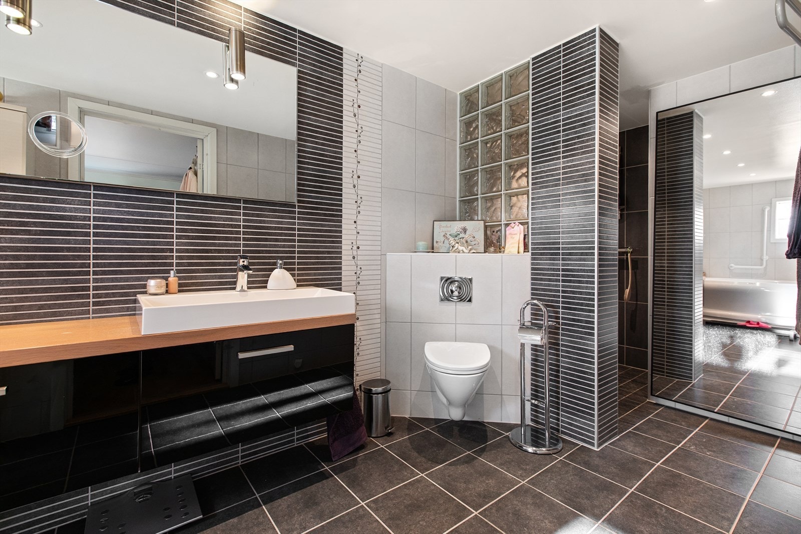 Badet er innredet med vegghengt toalett, servant på skuffeseksjon, dusjnisje og hjørnebadekar. Galleribilde