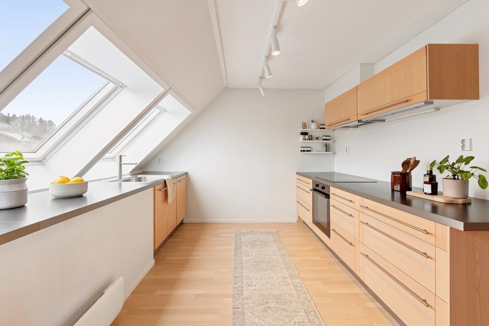 Kjøkkenet er godt utnyttet, med rikelig skap- og benkeplass samt store vinduer som slipper inn godt med lys. Alle hjørner er utnyttet for å gi maksimal arbeidsplass under matlaging. Galleribilde