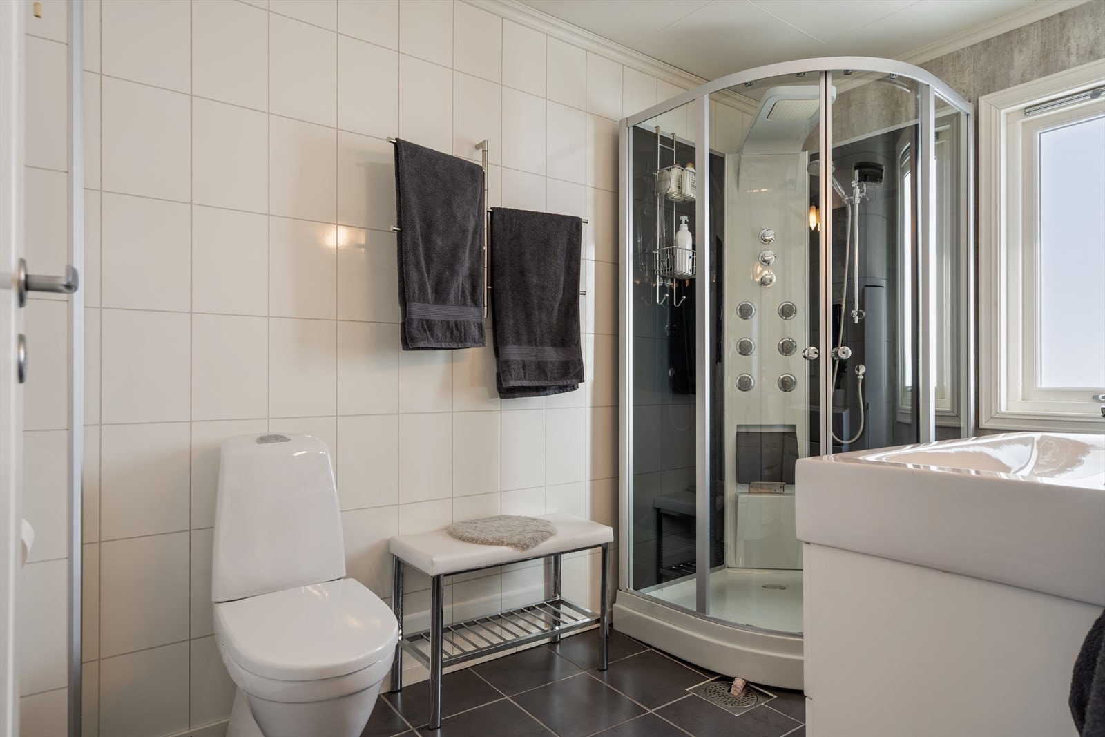 Romslig baderom innredet med dusjkabinett, baderomsseksjon med servant og toalett. Galleribilde