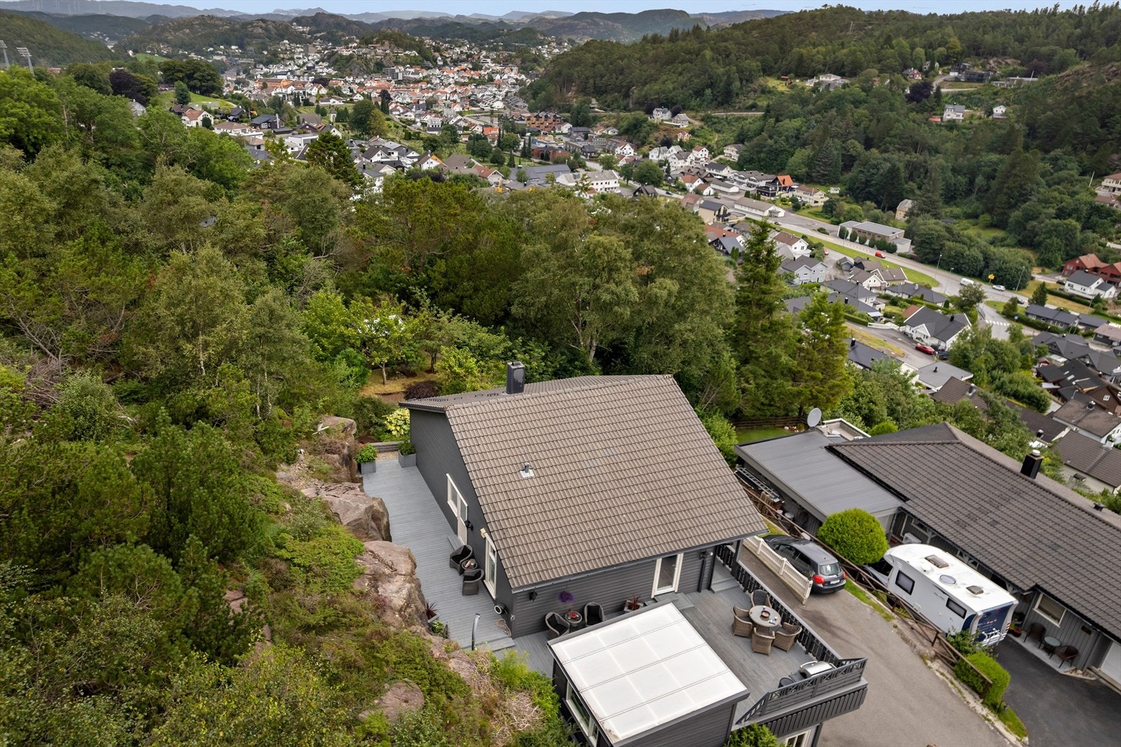 Uteområdet er pent opparbeidet med belegningsstein, beplantning og en romslig terrasse som slynger seg rundt boligen Galleribilde