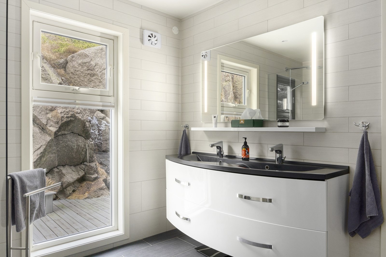 Hovedbadet i hovedetasjen er lekkert fliselagt og innredet med dobbel servant i benkeskap samt. speil med lys og varme Galleribilde