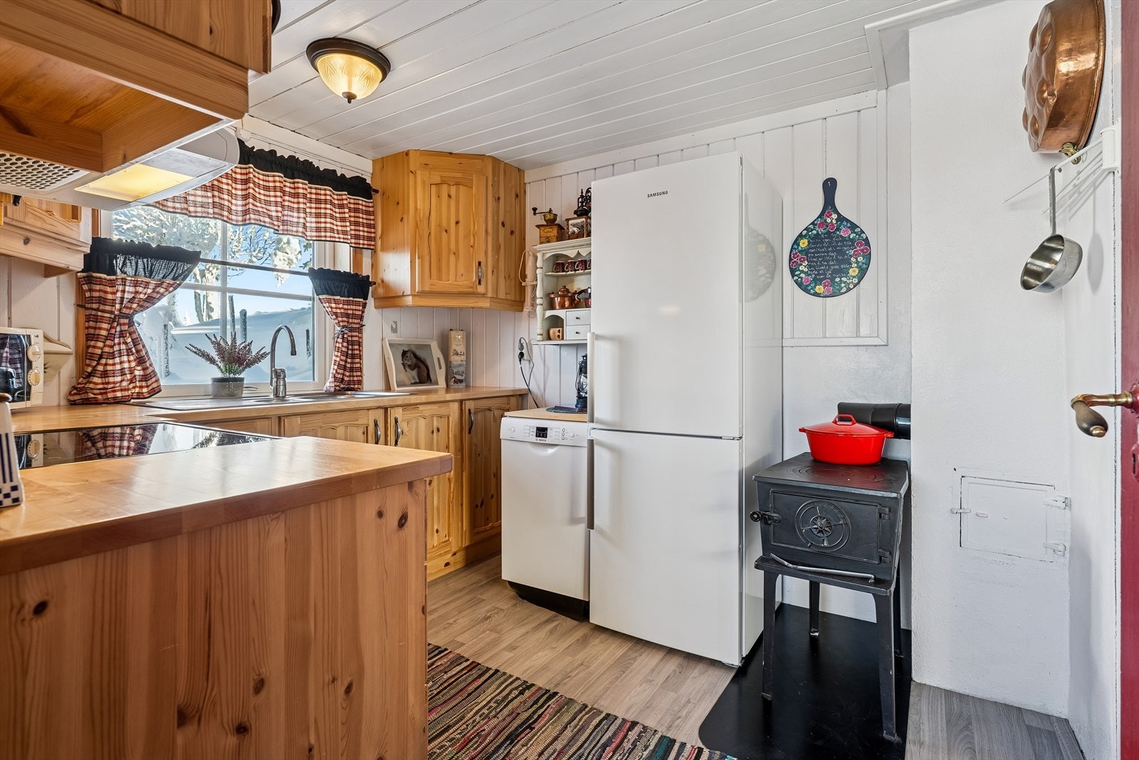 En eldre vedovn gir ekstra varme og skaper en lun atmosfære på kjøkkenet. Galleribilde