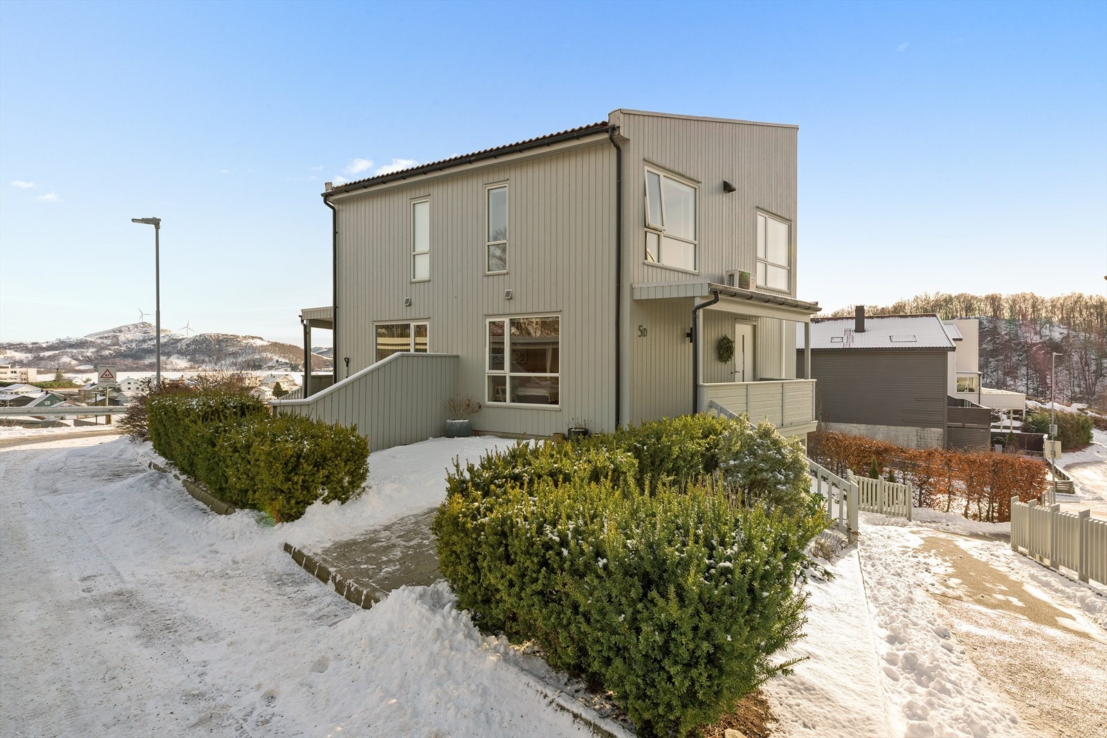 Boligen har flott inngangsparti med belegningstein, beplantning, et lite bed for de med grønne fingre og overbygget terrasse ved inngangsdør. Plass til sittegruppe. Galleribilde