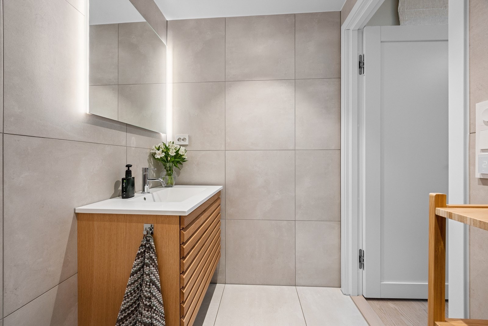 Badet tilknyttet hovedsoverommet har delikate store fliser på gulv og vegger, samt baderomsinnredning bestående av benkeskap med profilerte fronter. Galleribilde