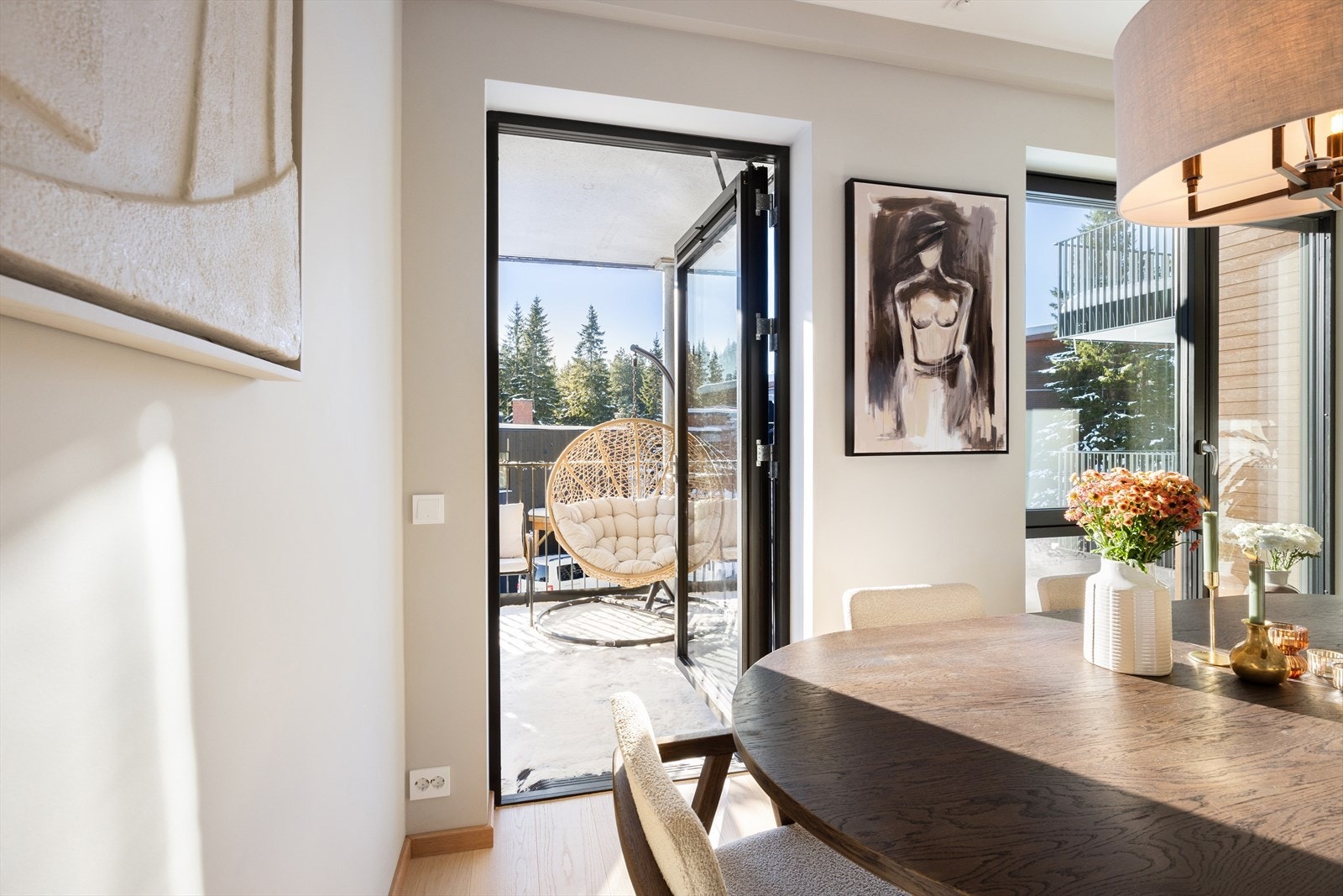 Utgang til solrik overbygget balkong. Spiseplassen, som ligger ved vinduene, fungerer som et naturlig og hyggelig samlingspunkt. Helheten gir en gjennomført og estetisk tiltalende stue der det er enkelt å trives. Galleribilde