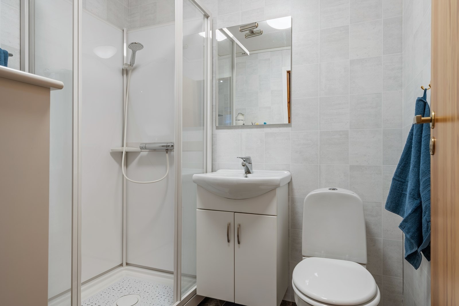 Leilighetens baderom er lyst og tidsriktig innredet med gulvbelegg på gulv og tapet på vegger. Galleribilde