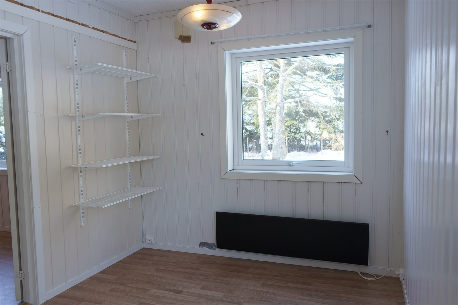 Soverom 2 har belegg på gulv, lysmalt panel på veggene og et stort vindu som slipper inn fint lys. Galleribilde