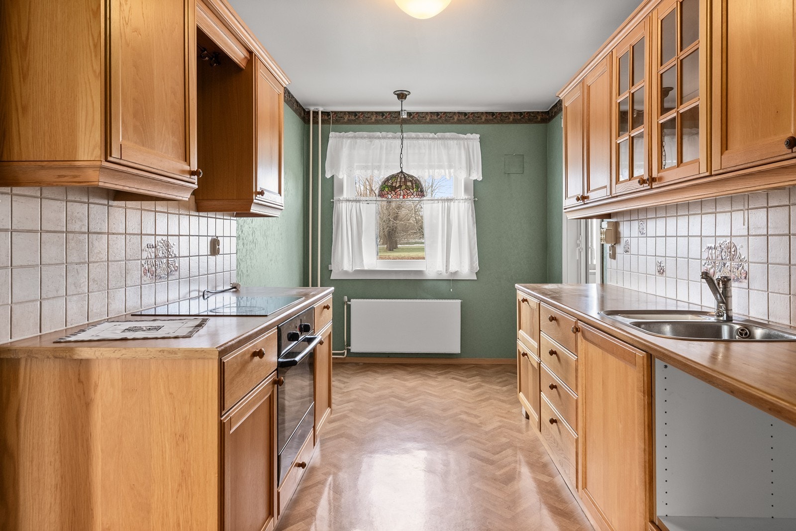 Kjøkkenet har en praktisk parallell-løsning med innredning med profilerte fronter og benkeplate i heltre. Galleribilde