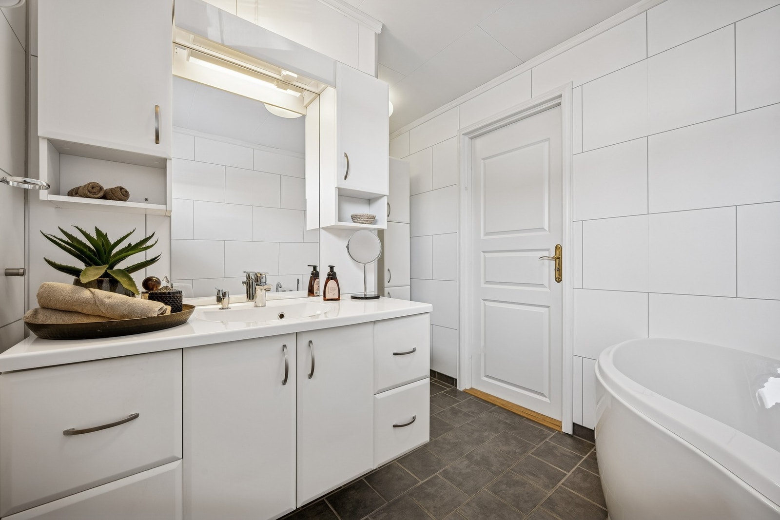 Badet har et stilrent uttrykk og rommer både baderomsinnredning, toalett, hjørnebadekar og romslig dusj Galleribilde