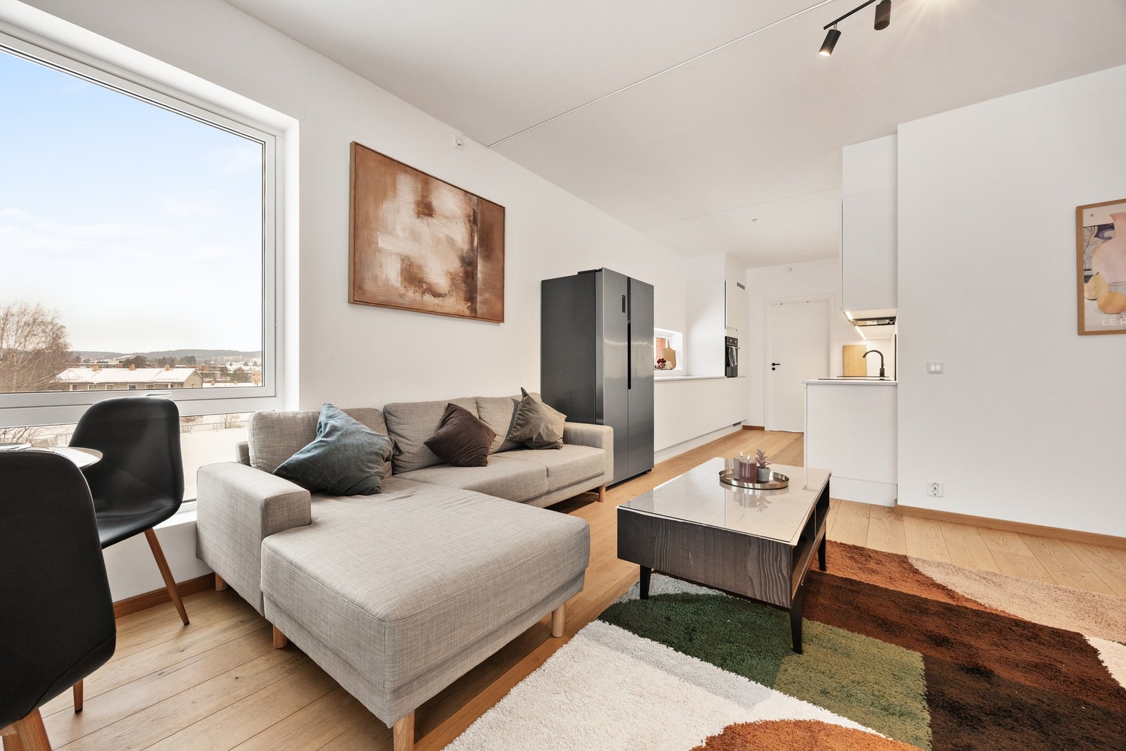 Lys, pen og romslig stue med åpen løsning til kjøkken. Store vinduer sørger for mye naturlig lysinnslipp Galleribilde