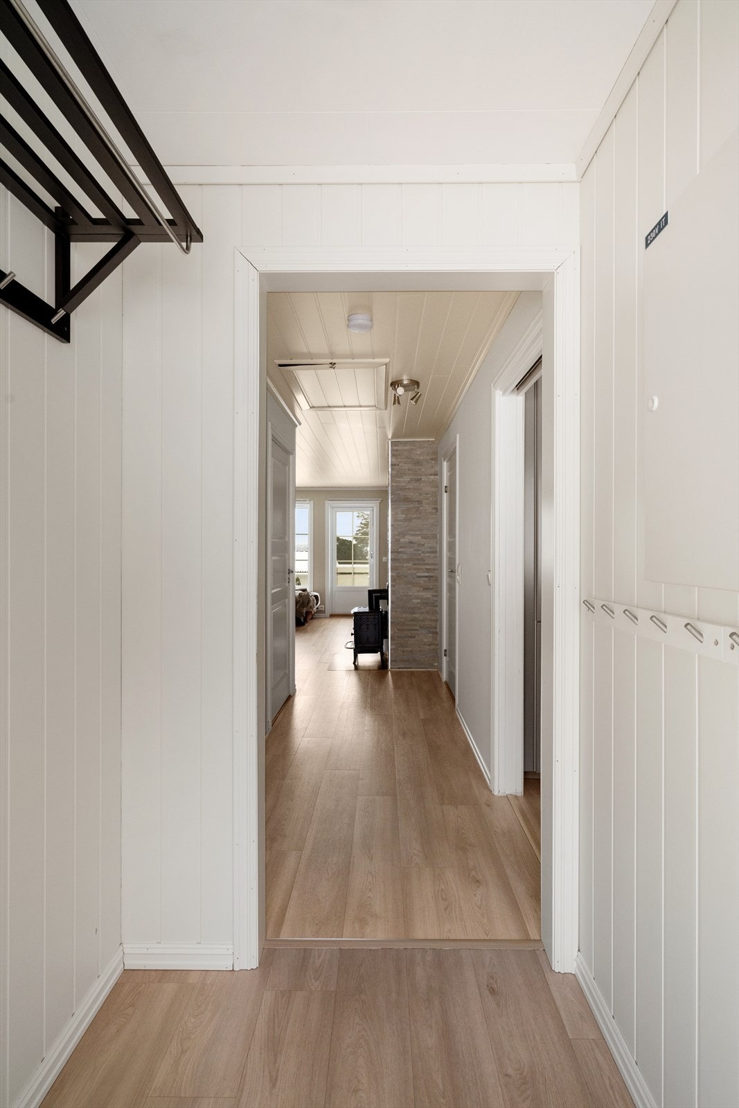 Med adkomst fra det hyggelige og usjenerte inngangspartiet kommer man inn i boligens gangarealer. I entrèen er det moderne laminat på gulvet som går videre innover og gir et helhetlig inntrykk. I entrèen er det sikringsskap, med nye sikringer fra 2021. Galleribilde