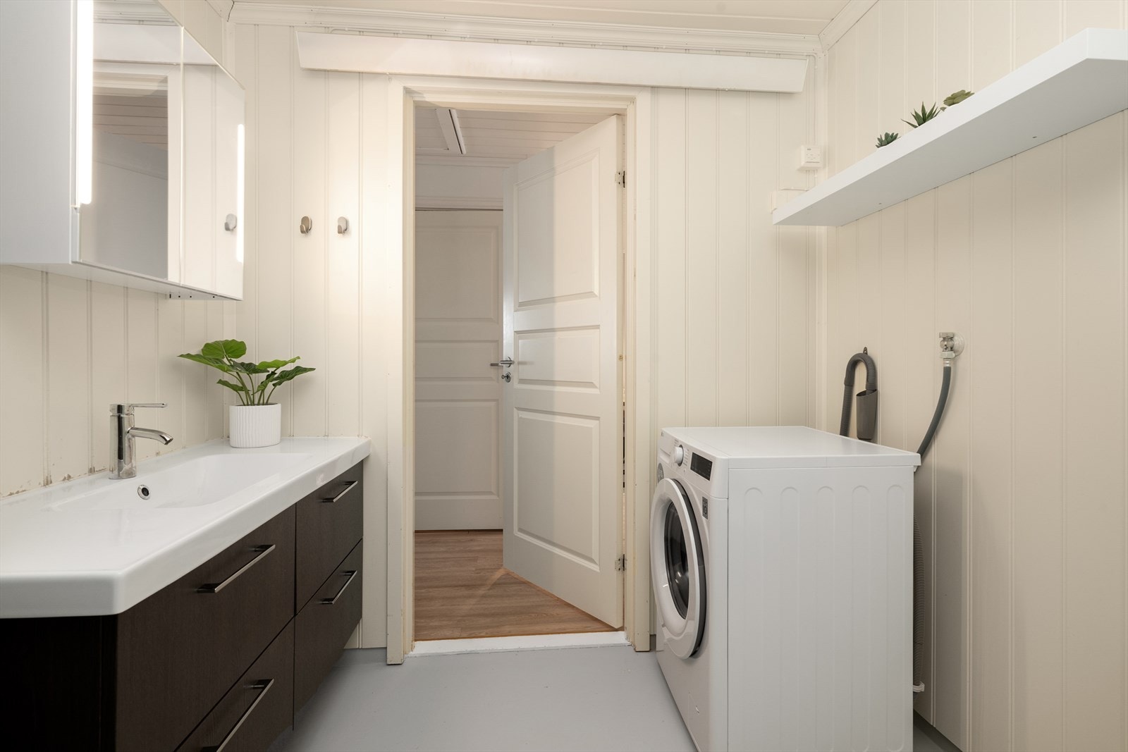 Badet er overflateoppusset i 2017 og har belegg på gulvet fra byggeår og mdf-plater på veggene. Varme via varmelist over dør. Galleribilde