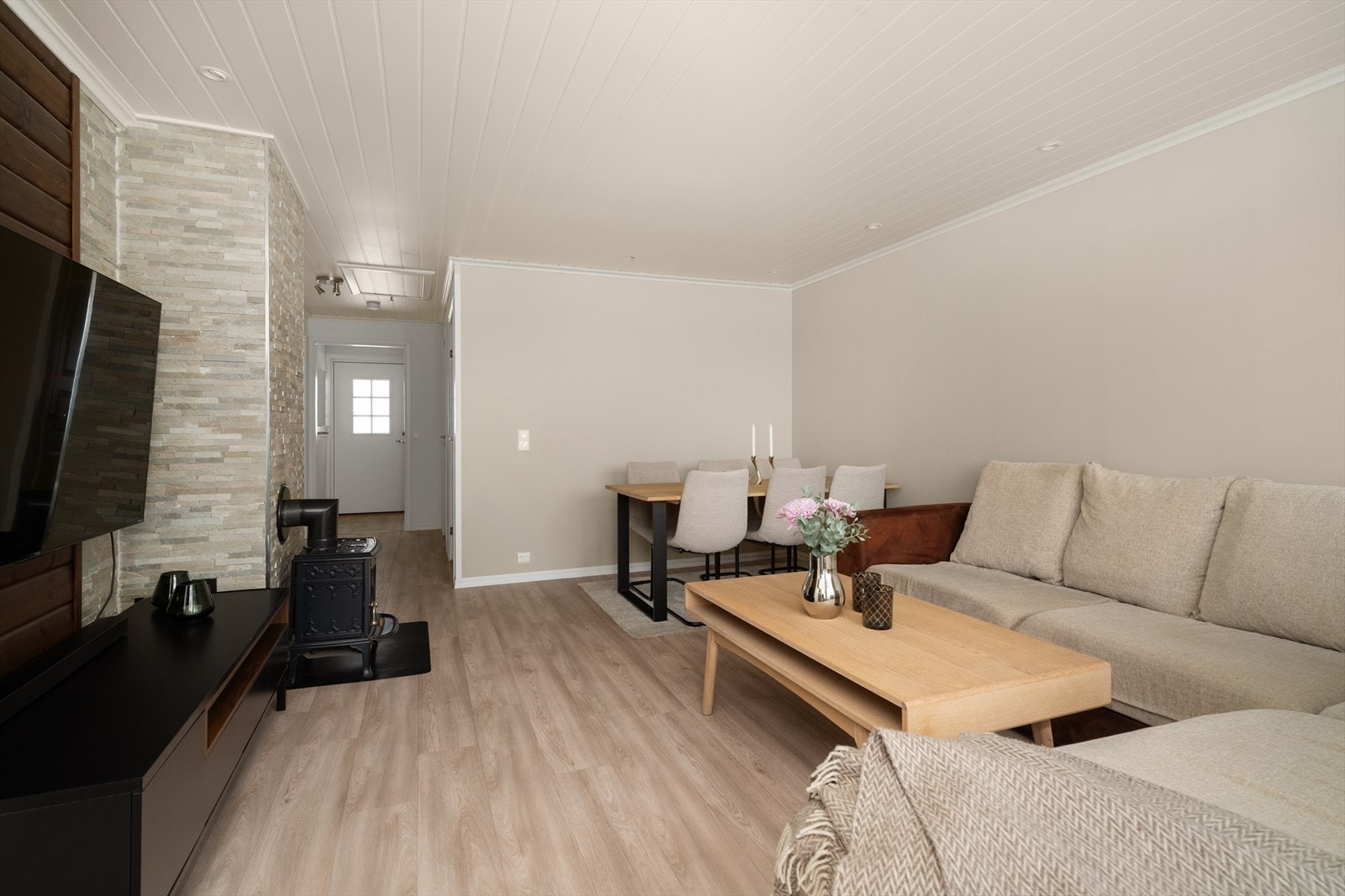 Stua har duse og delikate fargetoner, samt spennende innslag av dekorativ skiferstein og mørkbeiset panel. Det er installert vedovn med glassdør for lun varme på kjølige dager. Galleribilde