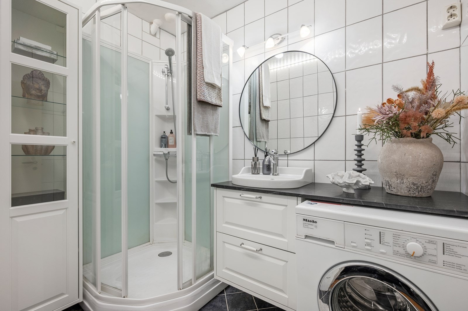 Flislagt bad med varmekabler i gulv. Innredet med dusjkabinett, servantskap, skap, speil og opplegg for vaskemaskin. Galleribilde