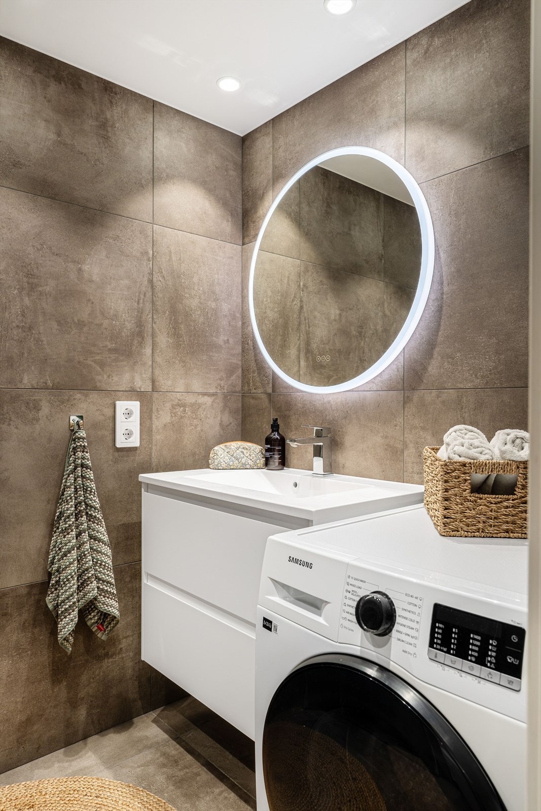 Badet er utstyrt med servant med underskap, speil, vegghengt toalett, dusjhjørne med innfellbare dører, stor regndusj og opplegg for vaskemaskin. Galleribilde