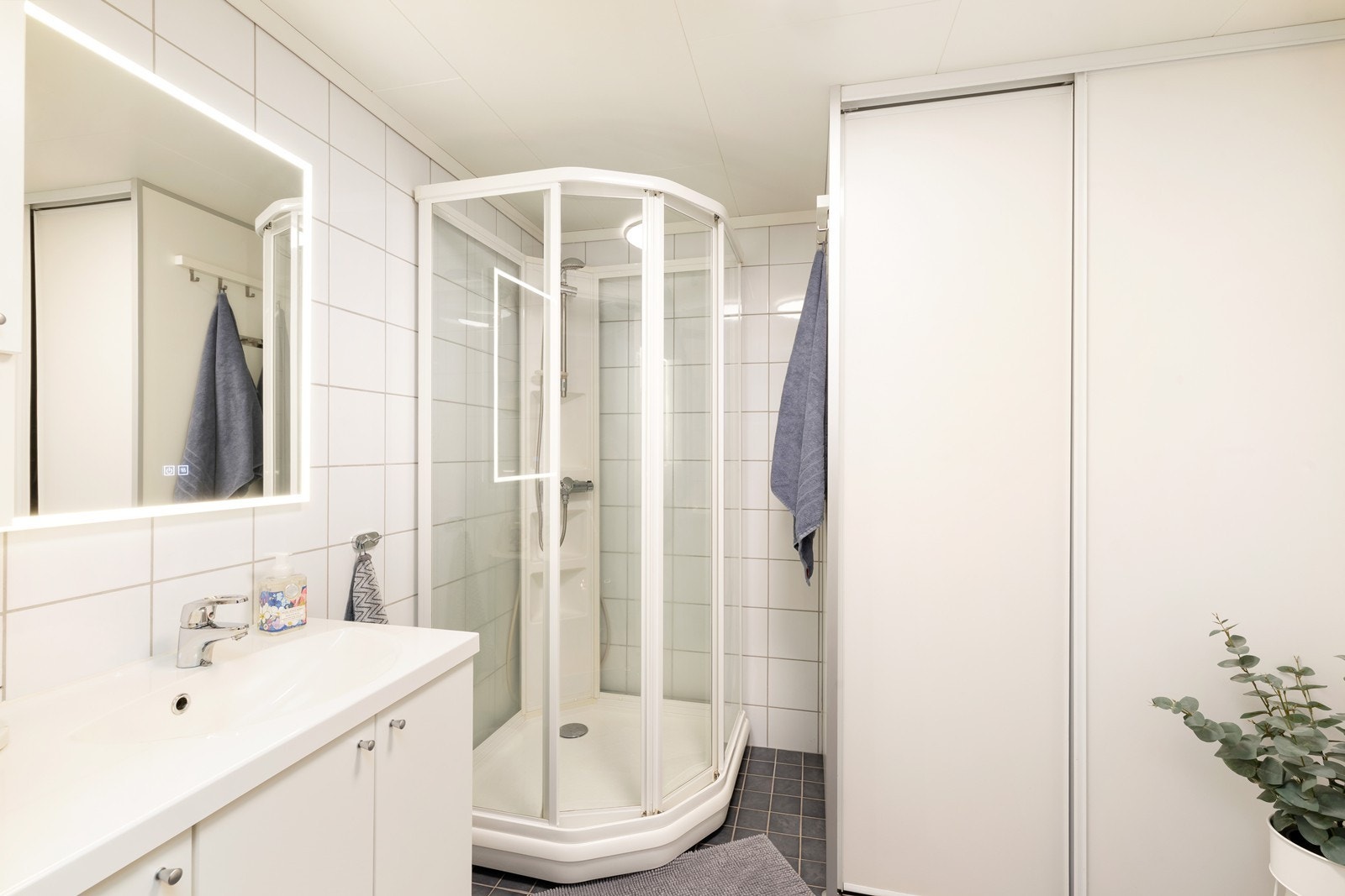 Flislagt bad med dusjkabinett, vegghengt toalett og servant med underskap. Galleribilde