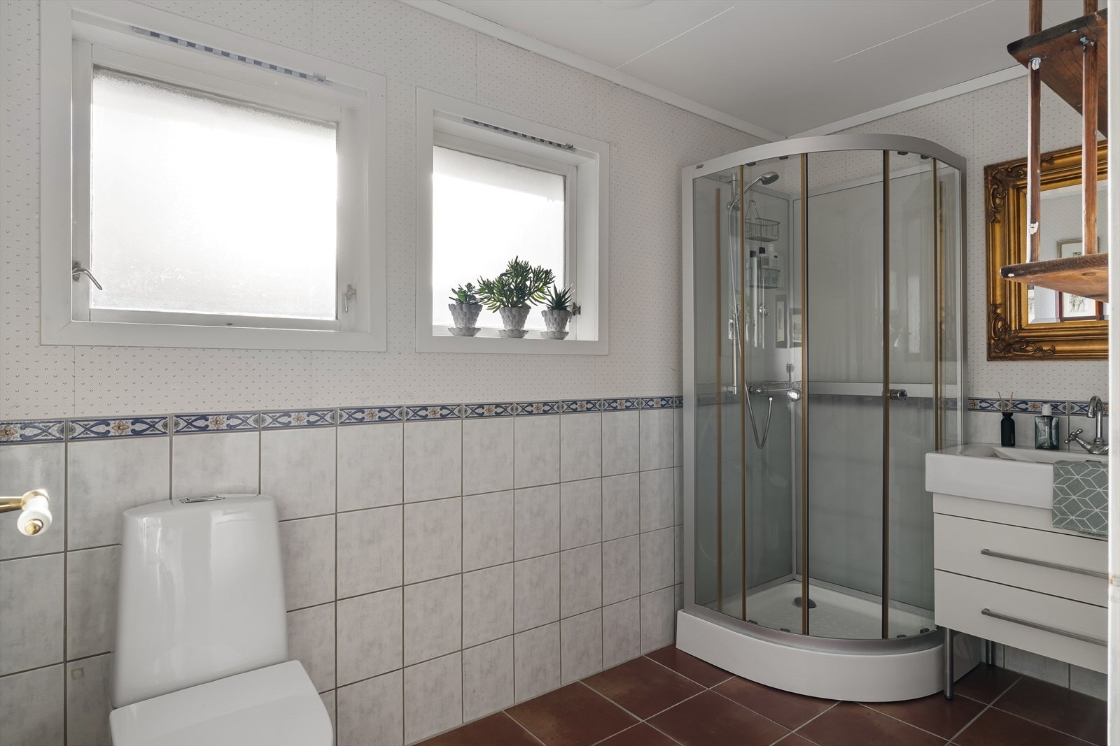 Bad med fliser på gulv og delvis vegg som inneholder wc, dusjkabinett, vask i seksjon og varme i gulv for ekstra komfort. Galleribilde