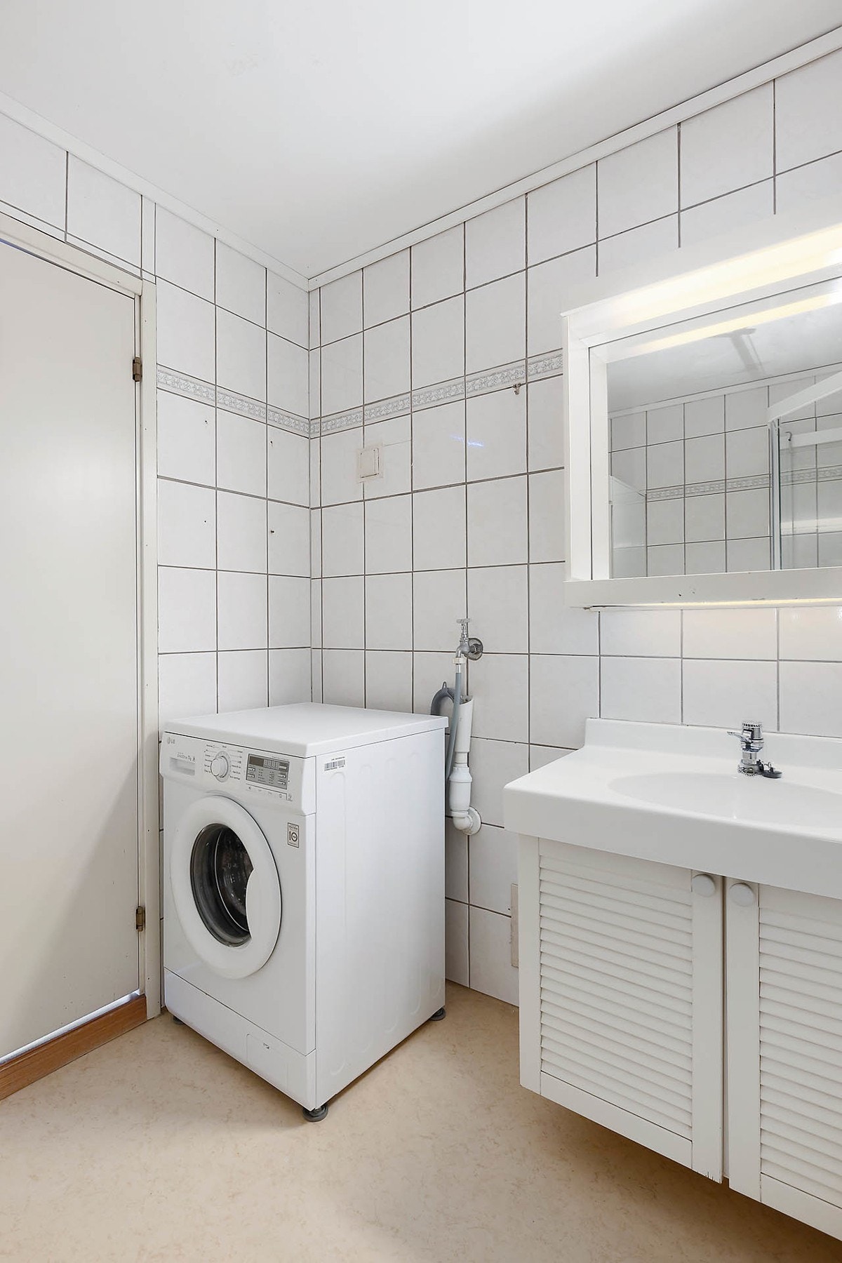 Eldre baderom med servant med underskap, dusjkabinett, tørkeskap og opplegg for vaskemaskin. Galleribilde