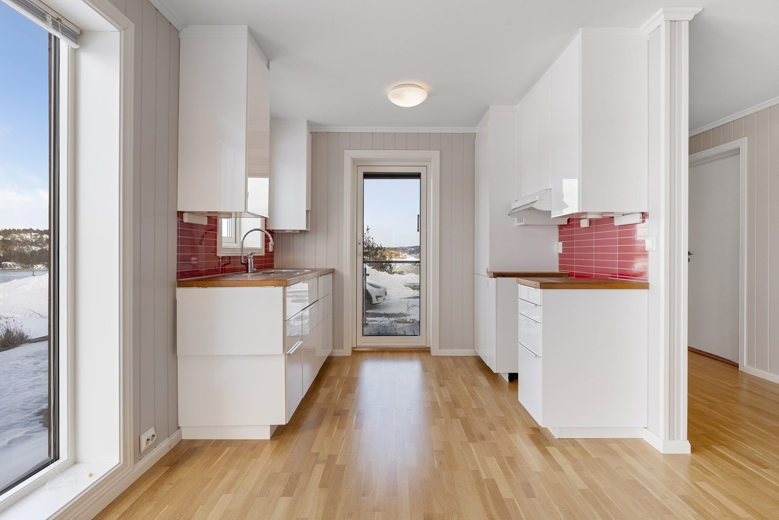 Kjøkken med hvite fronter og benkeplate i tre. Direkte utgang til terrasse og uteområde fra kjøkkenet. Galleribilde