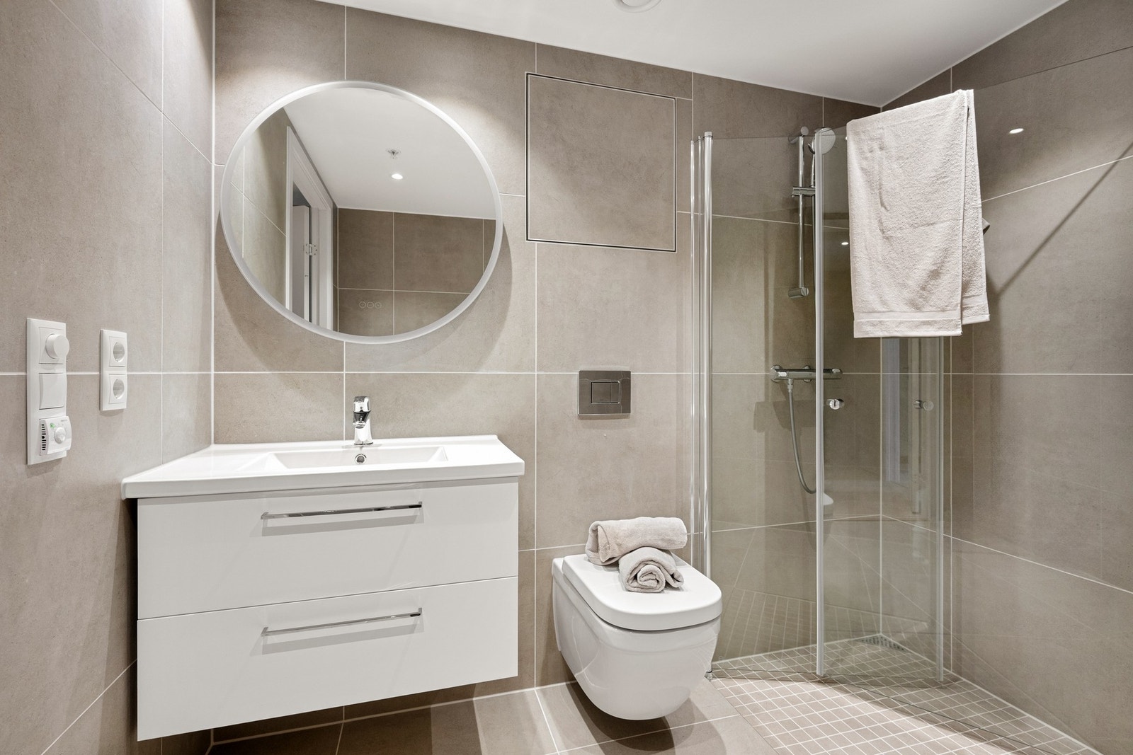 Varmekabler i gulvet sørger for en behagelig temperatur året rundt. Innredningen består av en heldekkende servant med to romslige underskuffer i hvit utførelse, som gir god oppbevaringsplass til det du trenger i hverdagen. Galleribilde