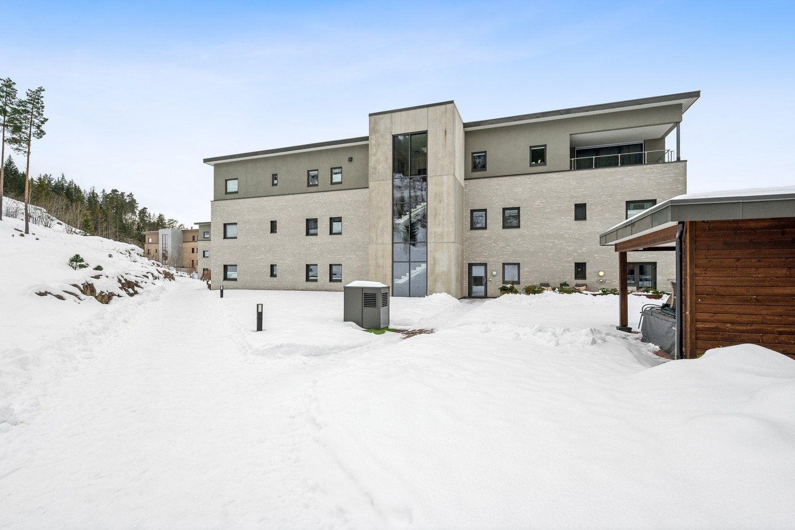 Bilde av baksiden av blokken. Her ser man også leilighetens uteplass rett frem i bildet. Galleribilde